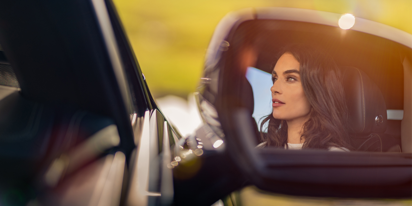 Bentley Warszawa profile of dark haired woman's face in mirror of Bentley car in sunlight