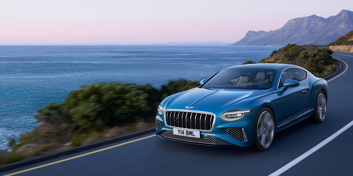 Bentley Warszawa New Bentley Continental GT Azure coupe in Light Windsor blue paint with 22 inch Azure wheels and chrome grill, driving dynamically by the sea