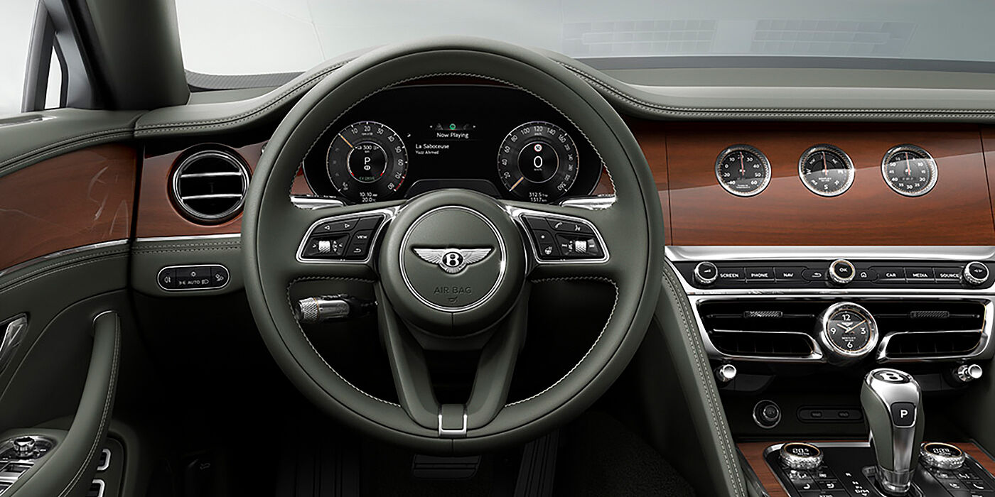 Bentley Warszawa New Bentley Flying Spur sedan front cabin in Cumbrian Green hide and Crown Cut walnut veneer showing steering wheel and Rotating Display with three clocks on face