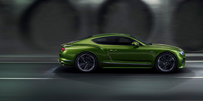  Bentley Warszawa Bentley Continental GT coupe in Tourmaline Green paint driving in profile on a dark road