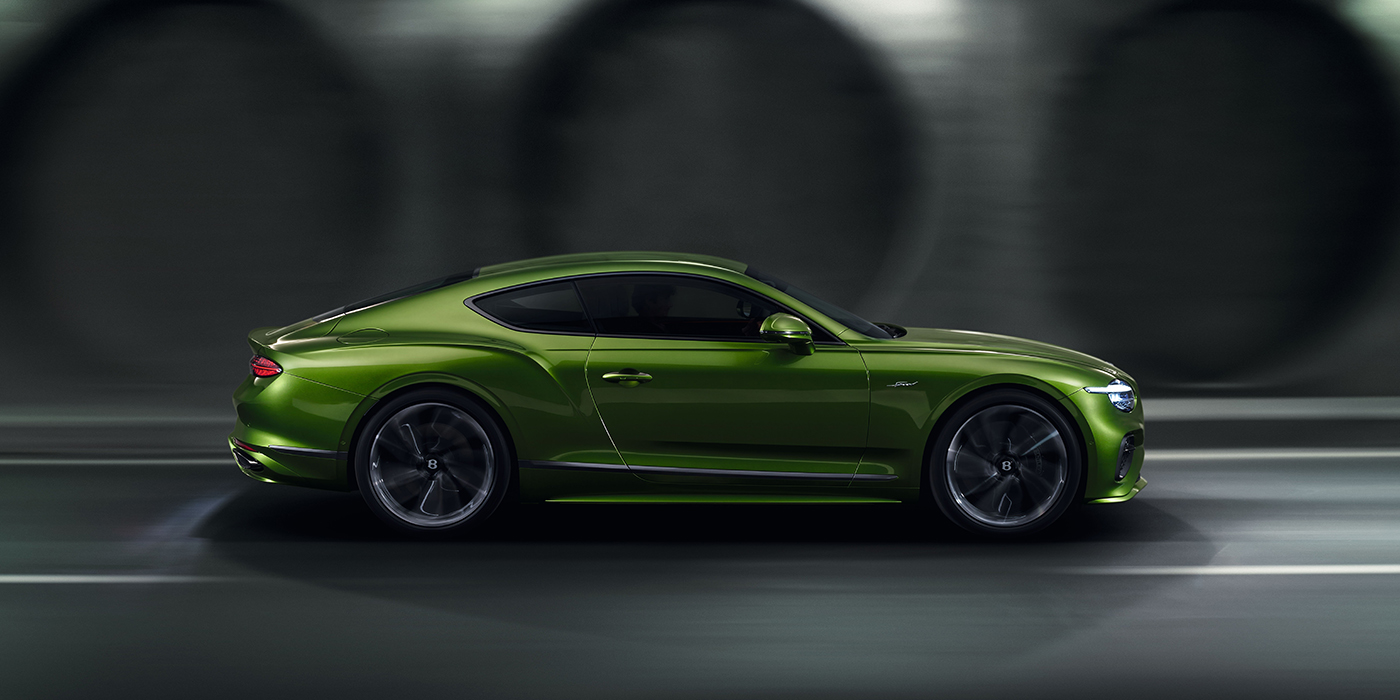 Bentley Warszawa Bentley Continental GT coupe in Tourmaline Green paint driving in profile on a dark road