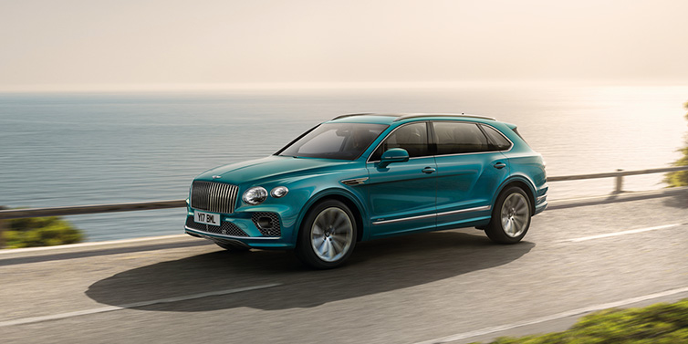 Bentley Warszawa Bentley Bentayga Extended Wheelbase Azure SUV in Topaz blue paint driving dynamically by the ocean