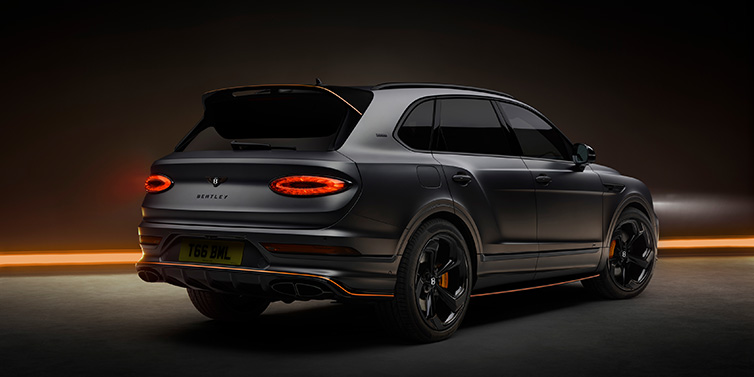 Bentley Warszawa Bentley Bentayga S Black Edition SUV rear three quarter in Anthracite Satin paint against a dark red and yellow background