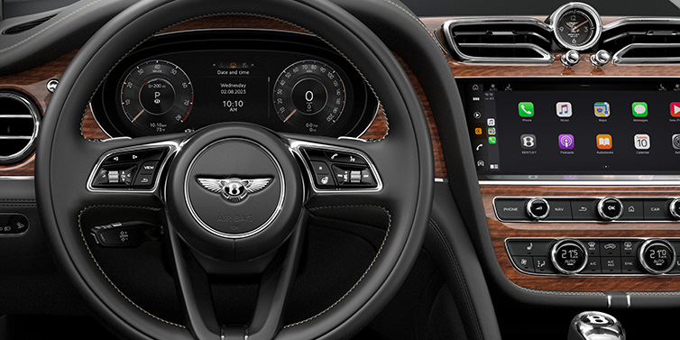 Bentley Warszawa Bentley Bentayga SUV front interior detail of steering wheel and driver screens surrounded by Beluga black hide and Crown Cut Walnut veneer