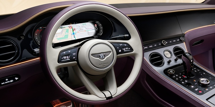 Bentley Warszawa Bentley Continental GT Mulliner coupe front interior showing steering wheel and drivers screens surrounded by Linen and Damson hides and Grand Black veneer