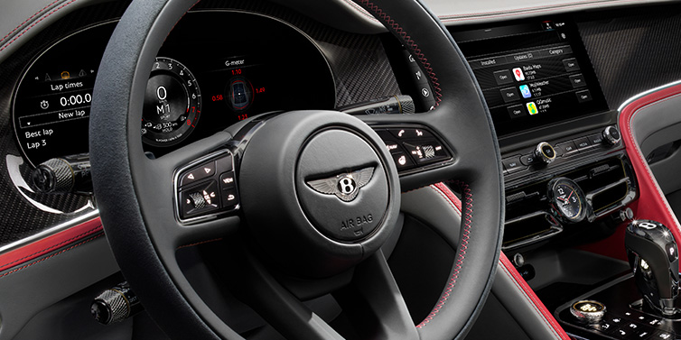 Bentley Warszawa Bentley Flying Spur Speed sedan front interior detail showing steering wheel and driver screens surrounded with Hotspur red and Gravity Grey hides